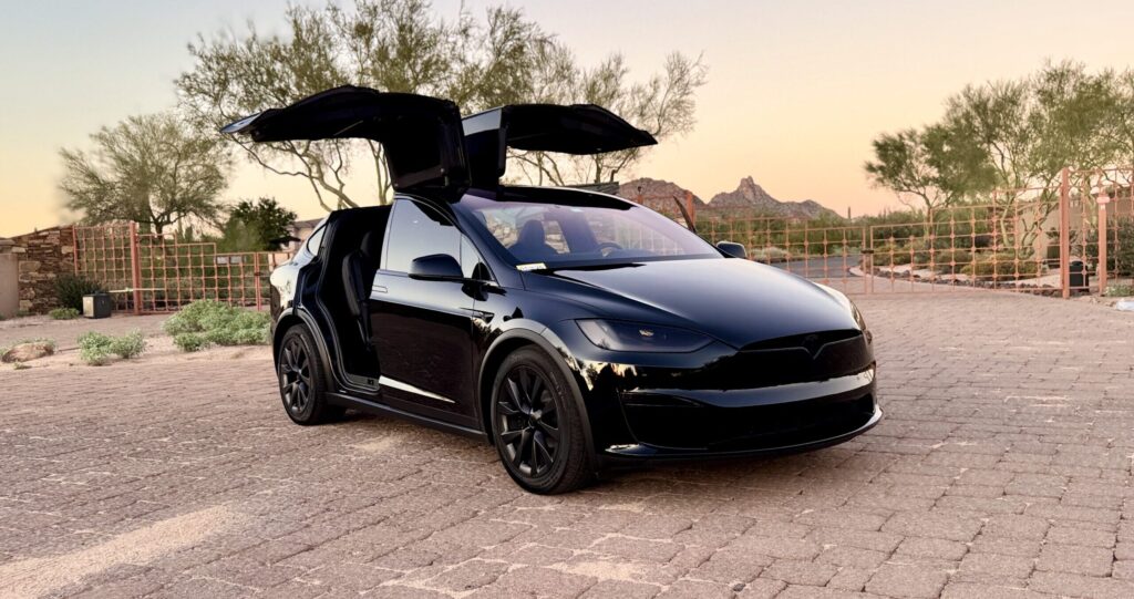 2025 Tesla Model Y rental car in black-on-black with black rims and tinted lights, parked in Scottsdale, AZ.